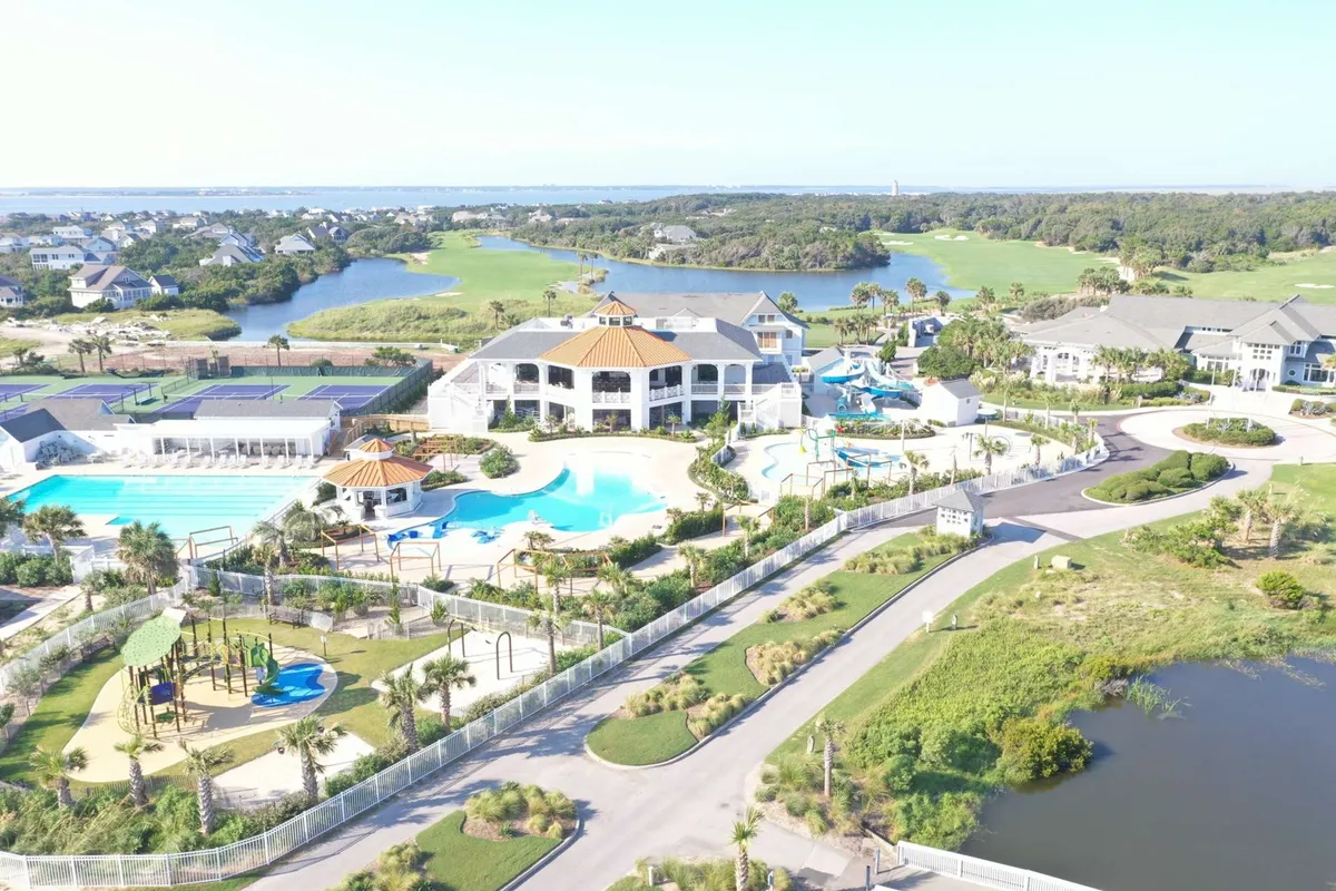 A vibrant exterior scene of a clubhouse with expansive swimming pools, water slides, a playground, and lush surrounding greenery. The atmosphere is lively and recreational, hinting at the upscale leisure options available to guests.