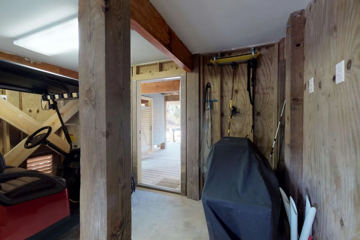 A garage interior with a golf cart parked near the doorway that opens to the outside, tools neatly arranged on the wall, and ample space for prepping for outdoor activities.