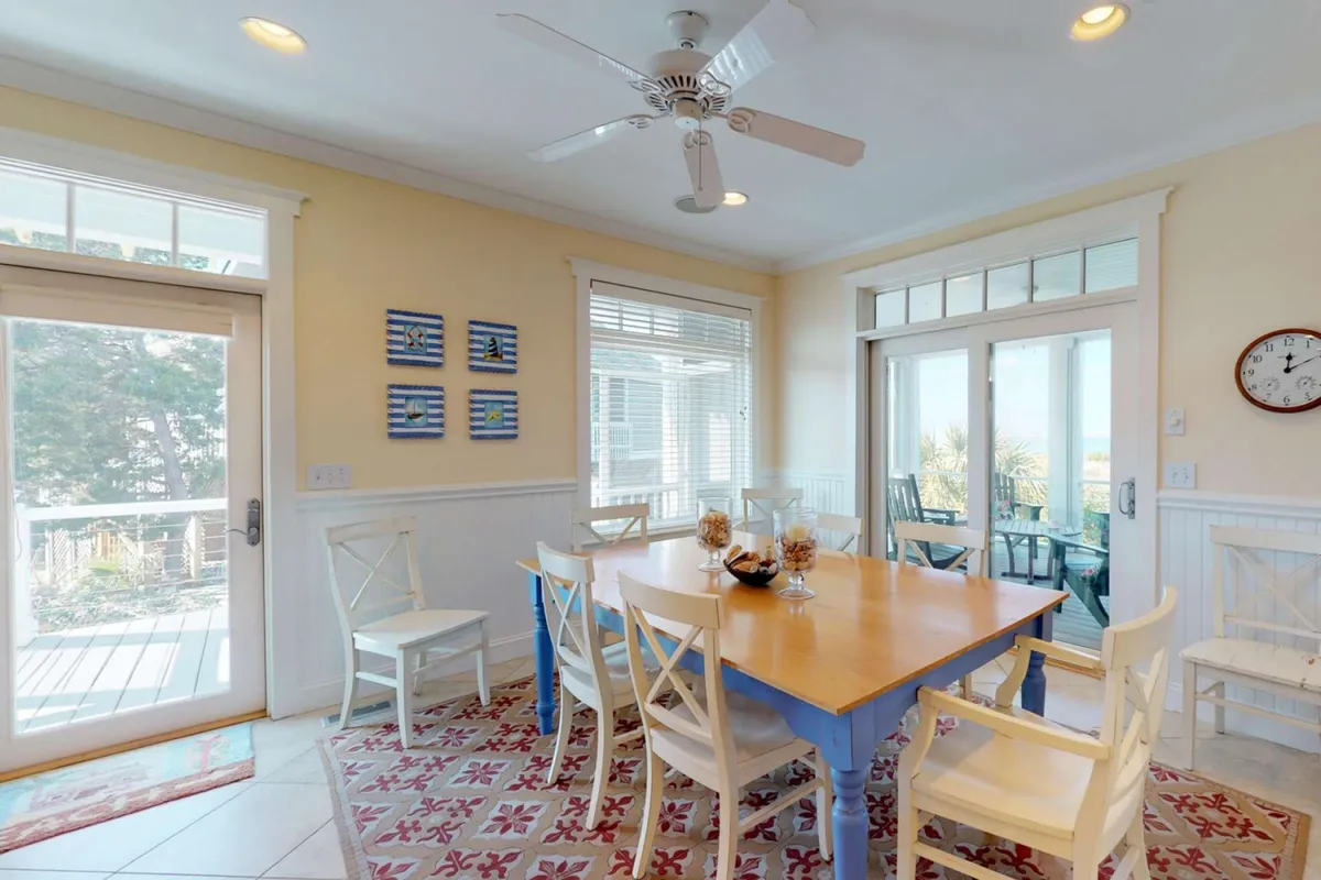 A cheerful dining area with a large table, window views, and art-adorned walls creates an inviting space for family meals, celebrations, and quiet mornings alike.